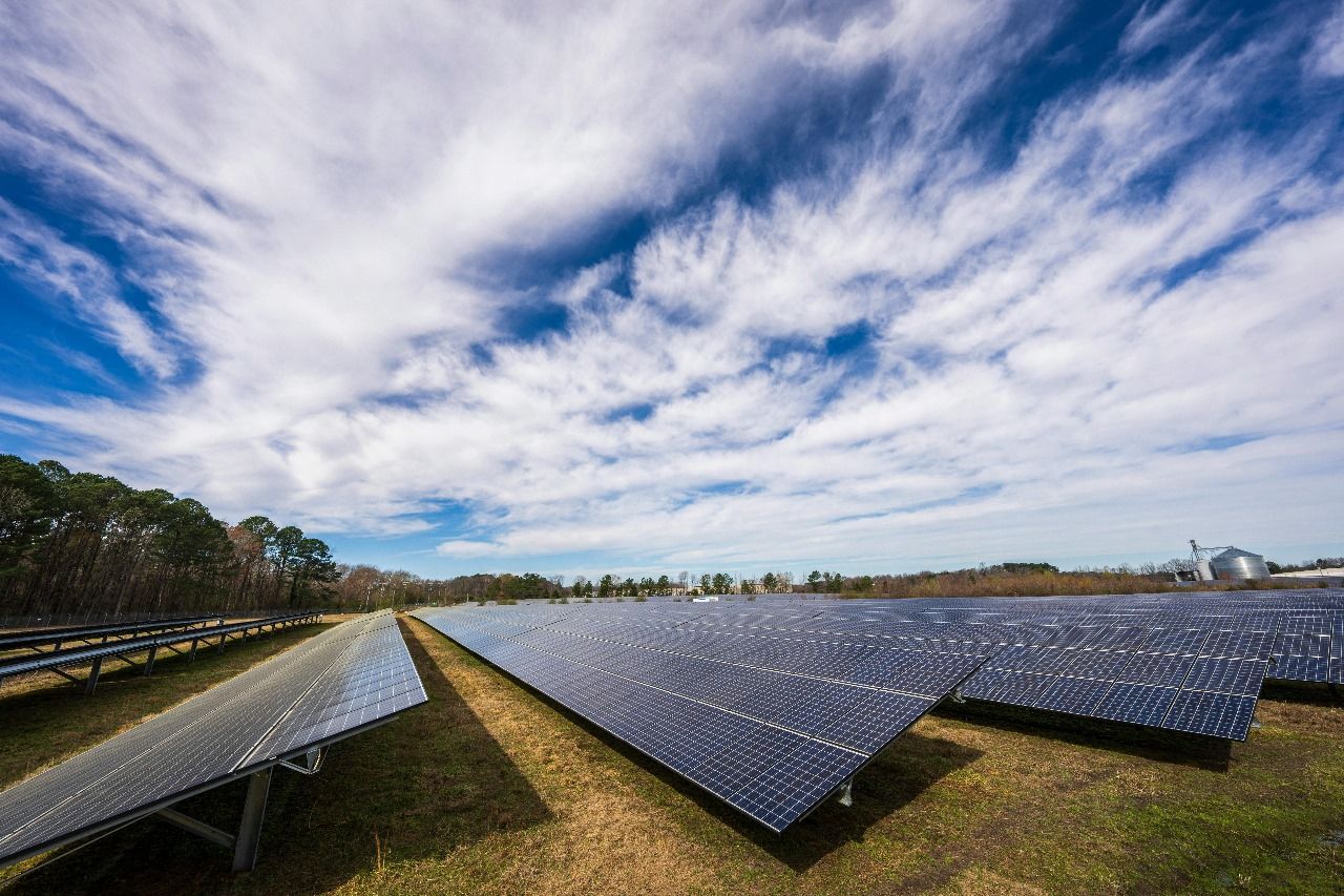 Ground-mounted solar array in open farmland under a clear sky.
